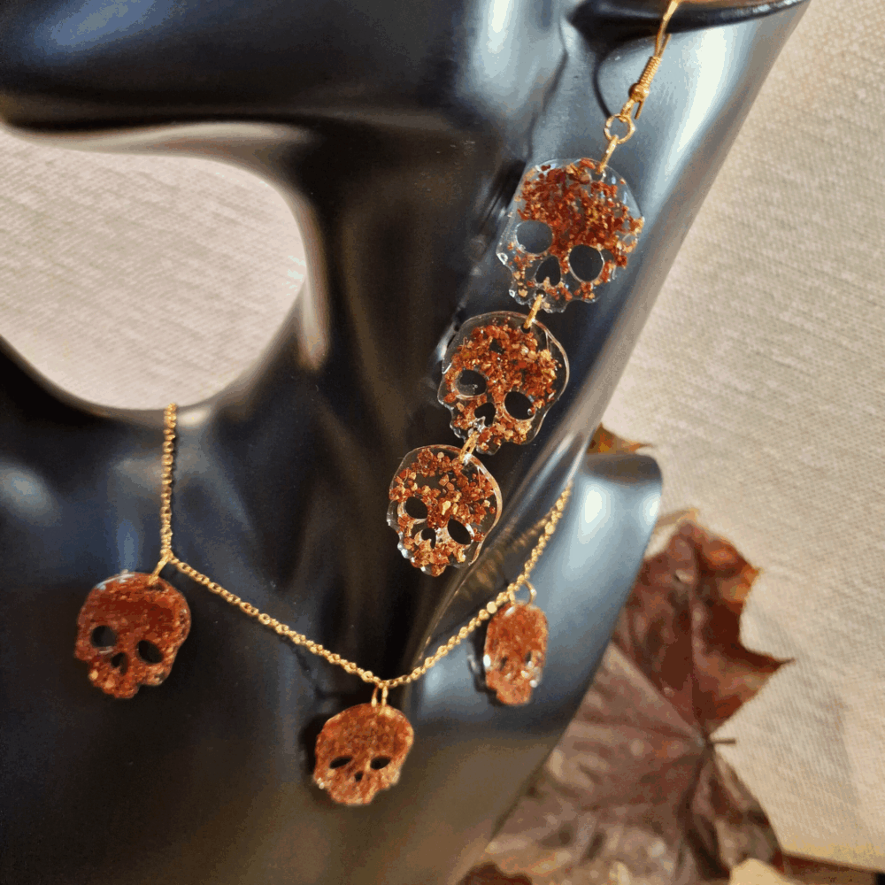 Parure artisanale Cé’rénité composée d’un collier et de boucles d’oreilles têtes de mort en résine et liège recyclé rouge doré, montures dorées.