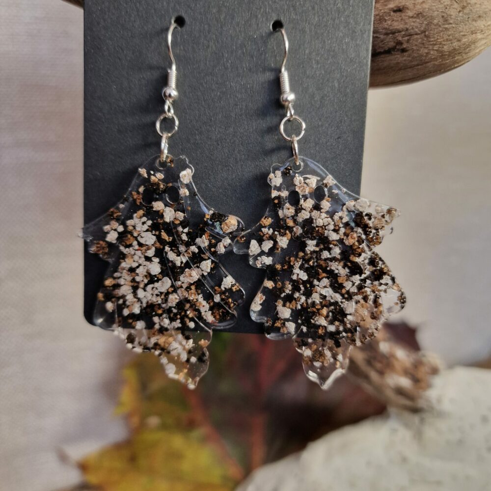 Boucles d’oreilles artisanales Cé’rénité en forme de petits fantômes, réalisées en résine transparente avec inclusions de liège naturel et éclats noirs, attaches argentées, longueur 8 cm.