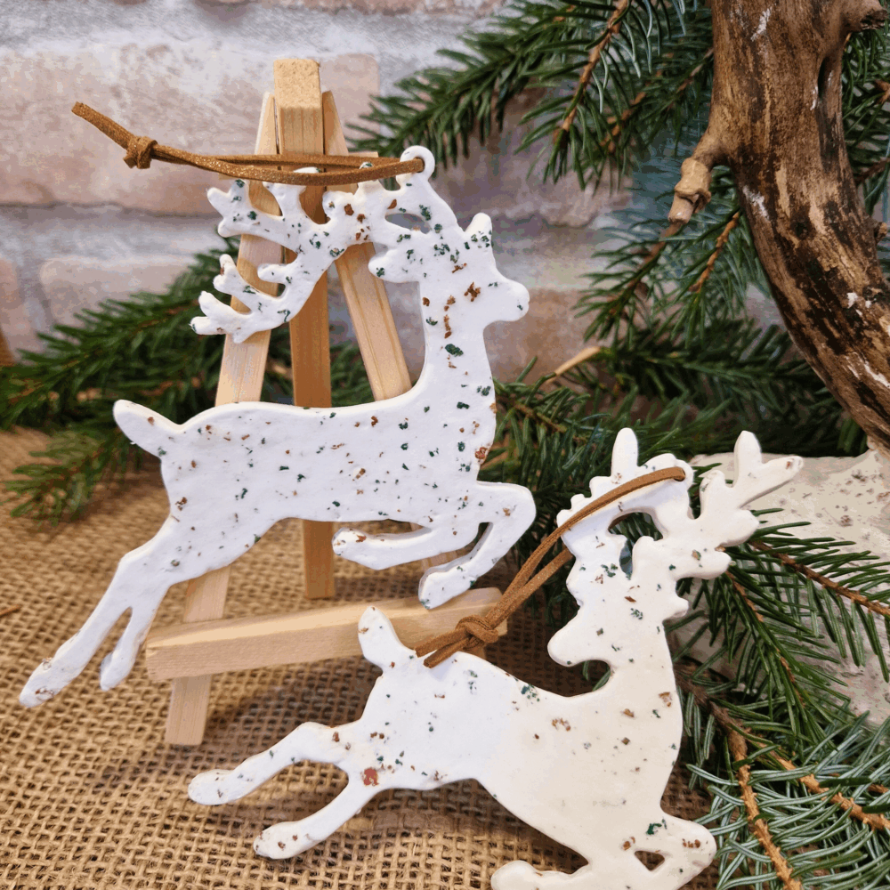 Deux suspensions rennes en argile blanche avec éclats de liège vert, rouge et naturel, cordon brun.