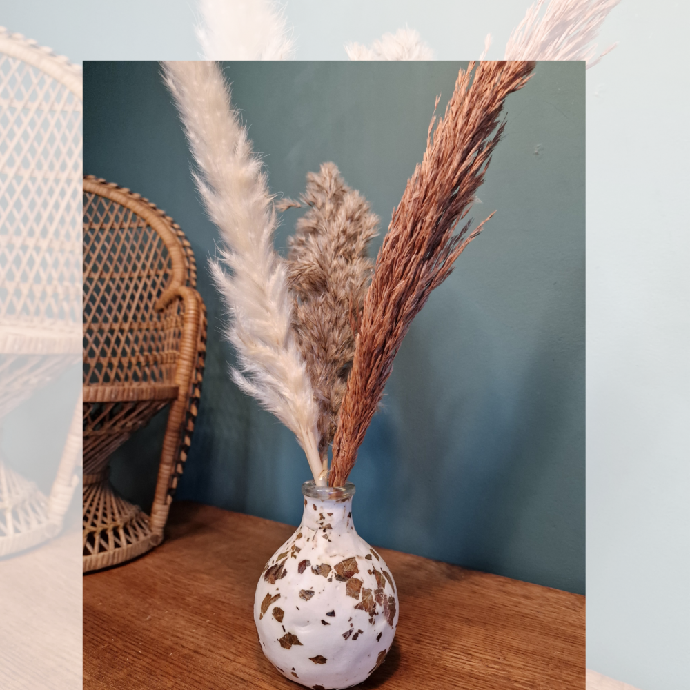 Vase artisanal en verre recyclé recouvert d’argile blanche avec feuilles naturelles incrustées.