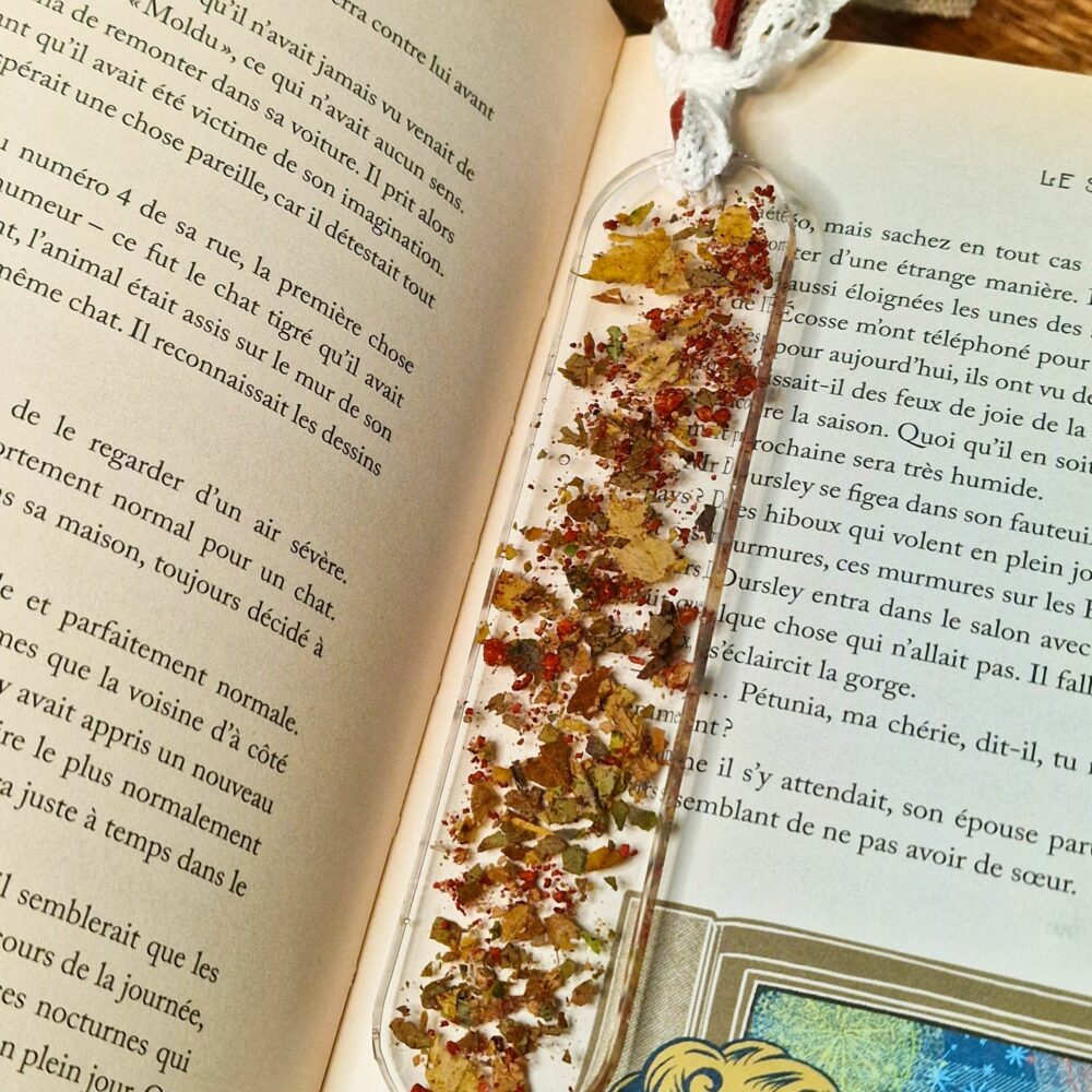 Marque-page artisanal en résine avec liège et feuilles naturelles posé sur un livre ouvert