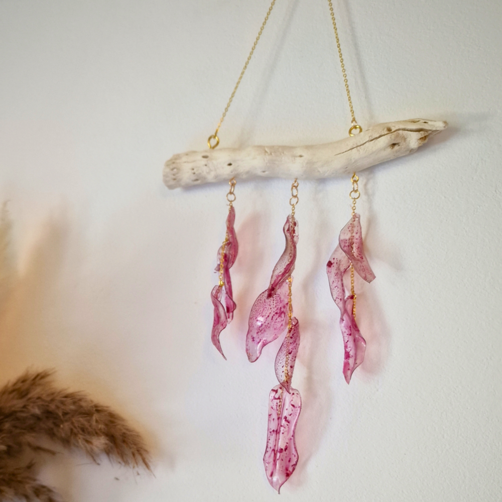 Suspension murale en plastique recyclé rose avec chaînes dorées et bois clair